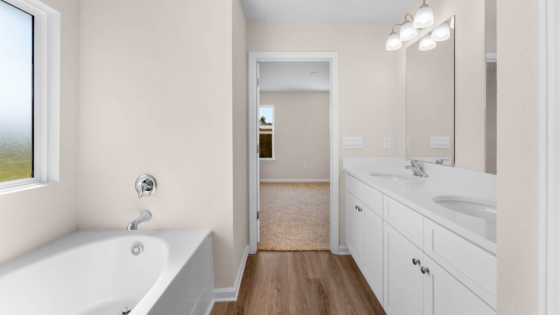 Primary bathroom with double vanity granite countertops and tub and closet.