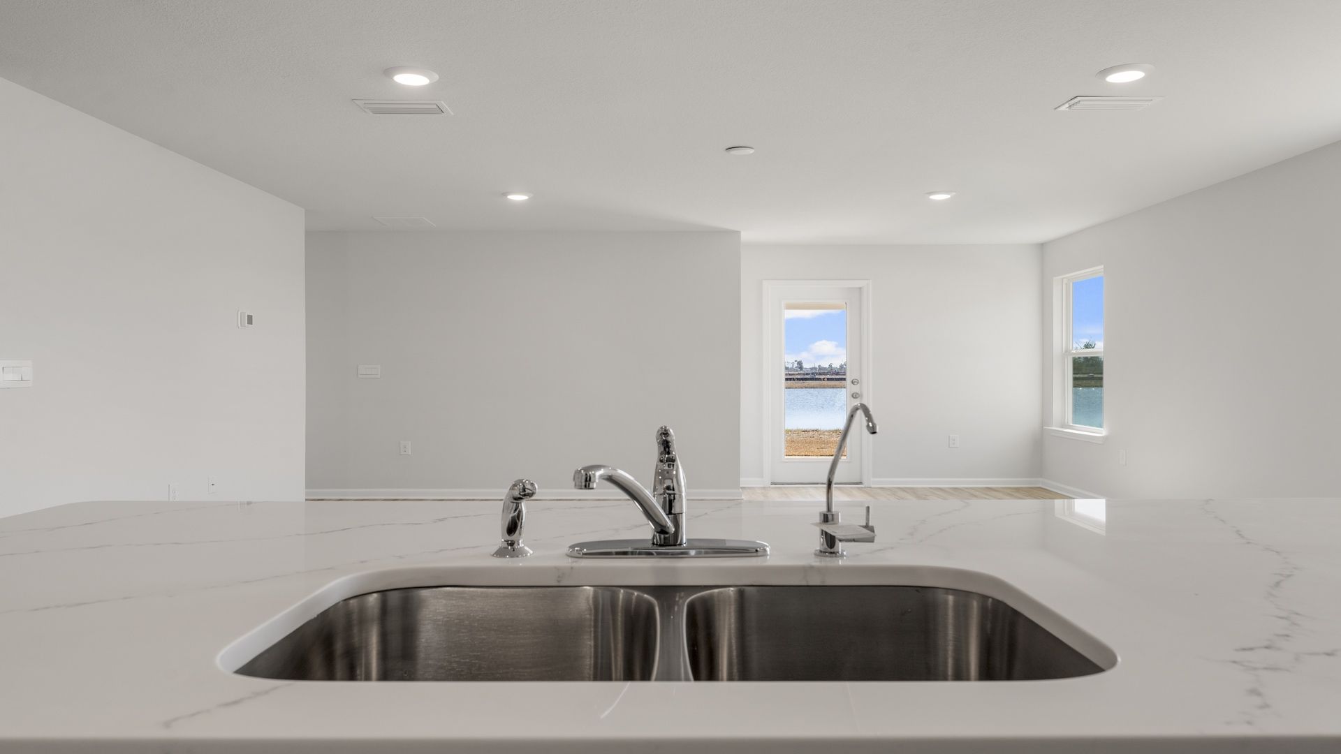 Kitchen island with quartz countertops undermount sink and back door and windows.