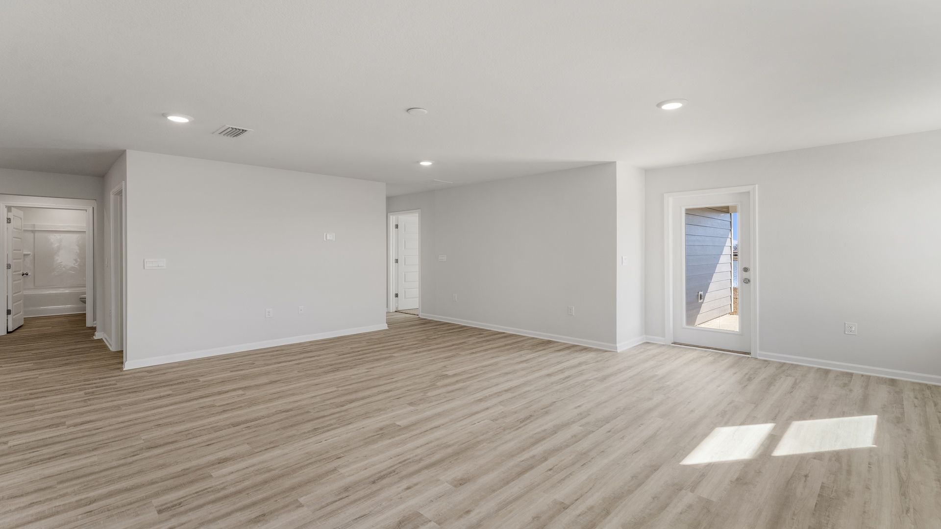 Open living room with EVP flooring and back door and window.