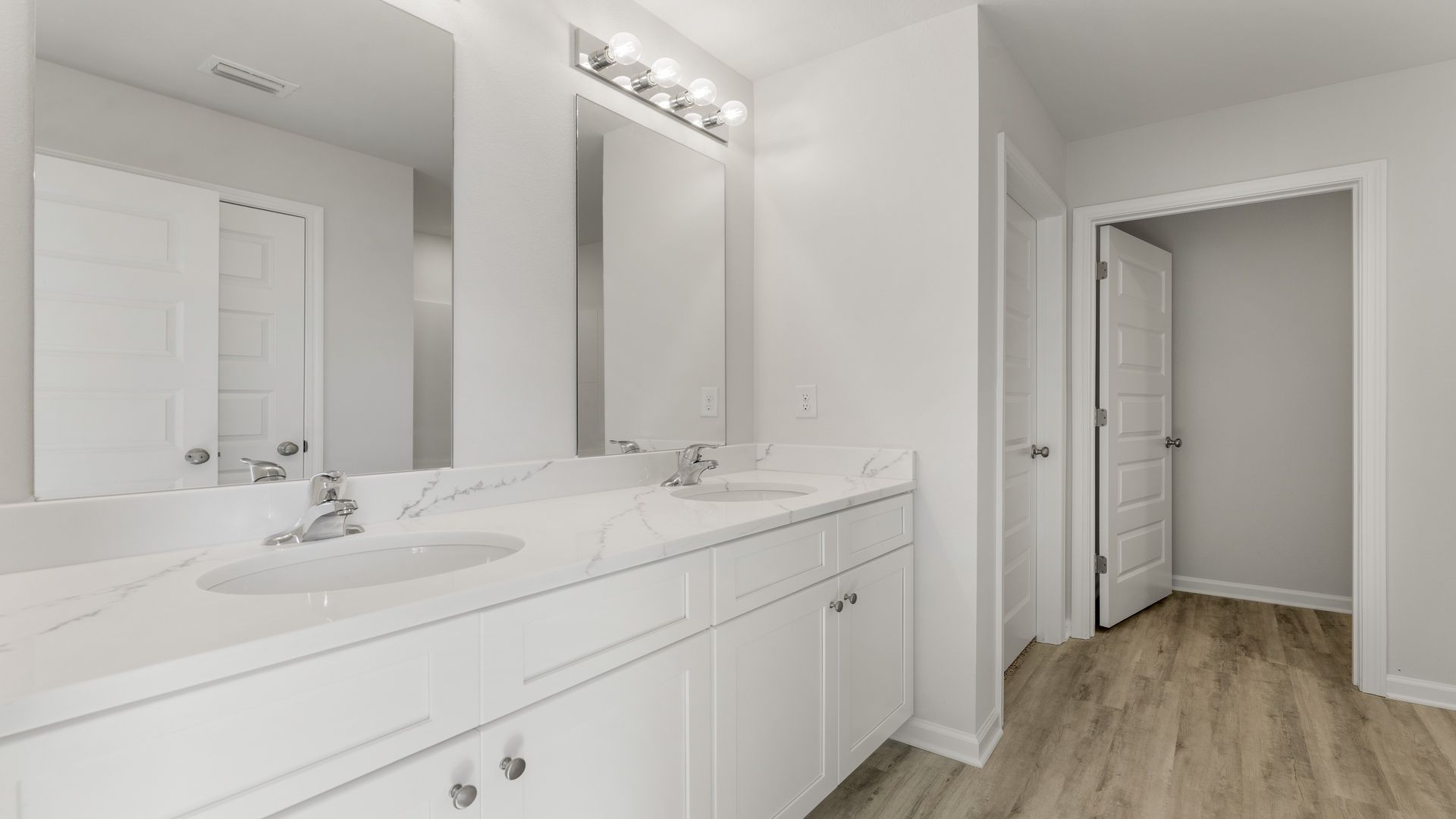 Primary bathroom with double vanity quartz countertops and EVP flooring and closet.