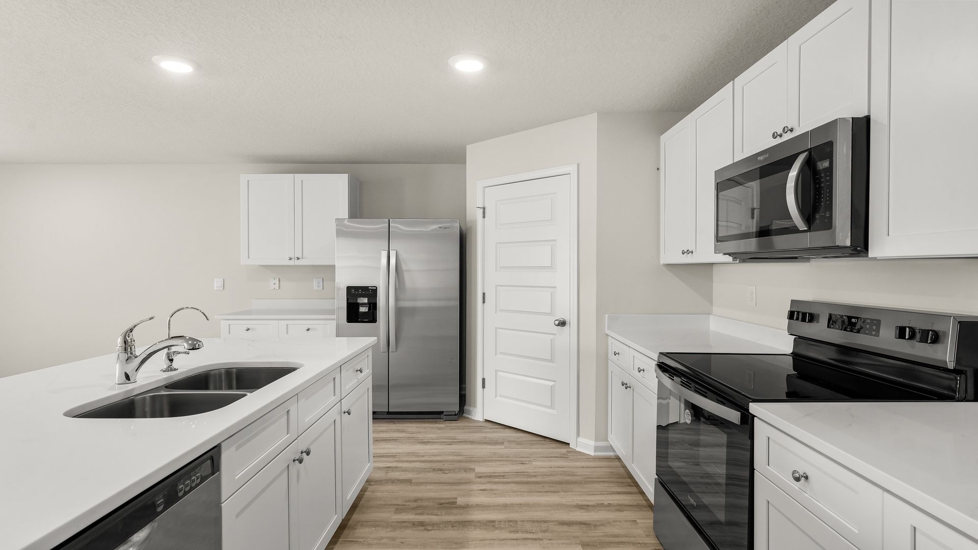 Kitchen island with white cabinets and stainless-steel appliances and quartz countertops and pantry.