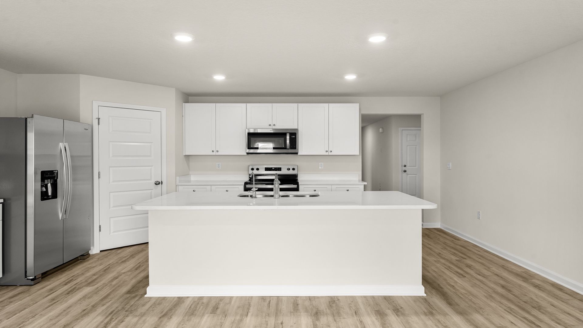 Kitchen island with white cabinets and stainless-steel appliances and quartz countertops and pantry.