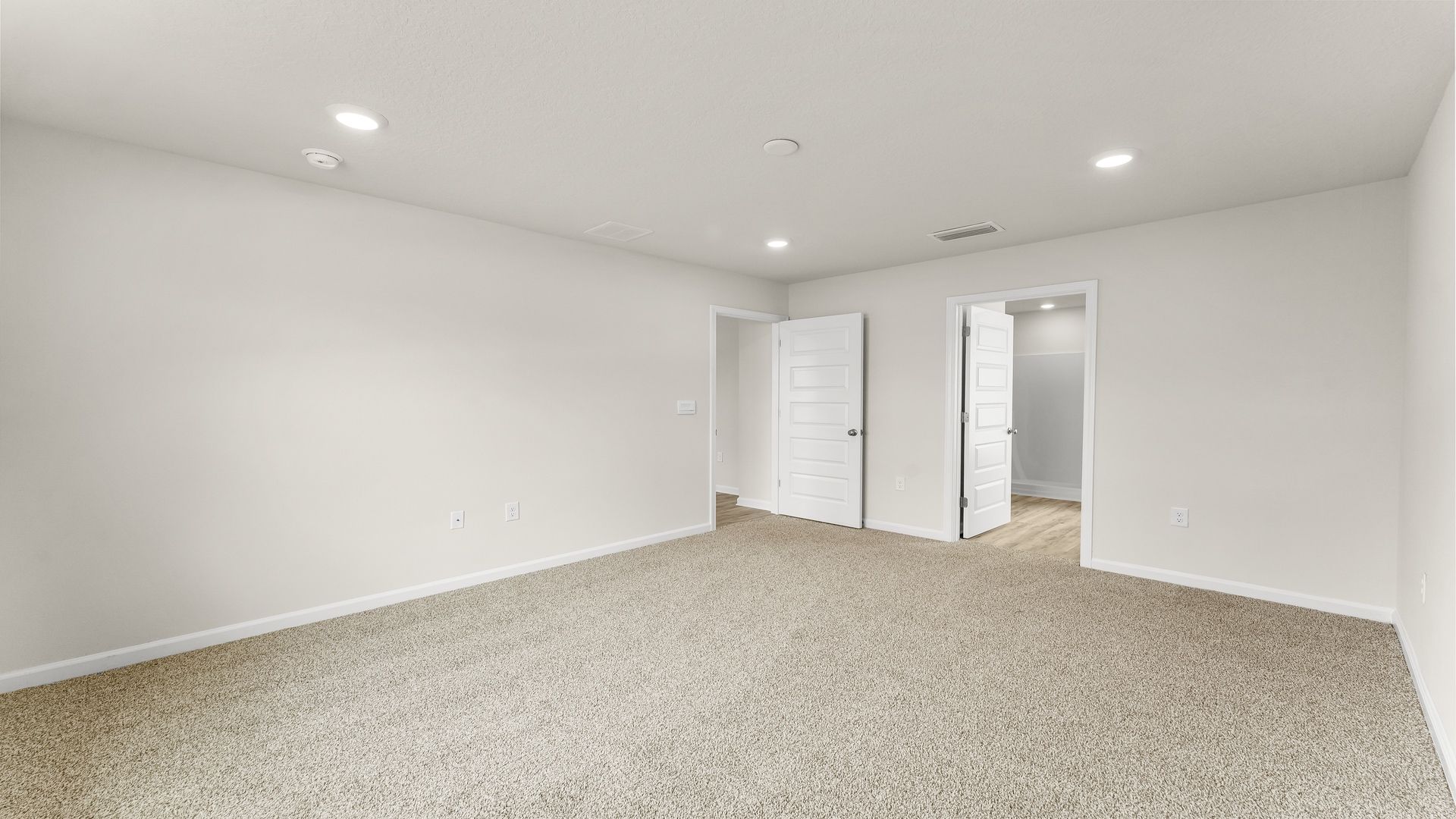 Primary bedroom with carpet floors and bathroom entrance.