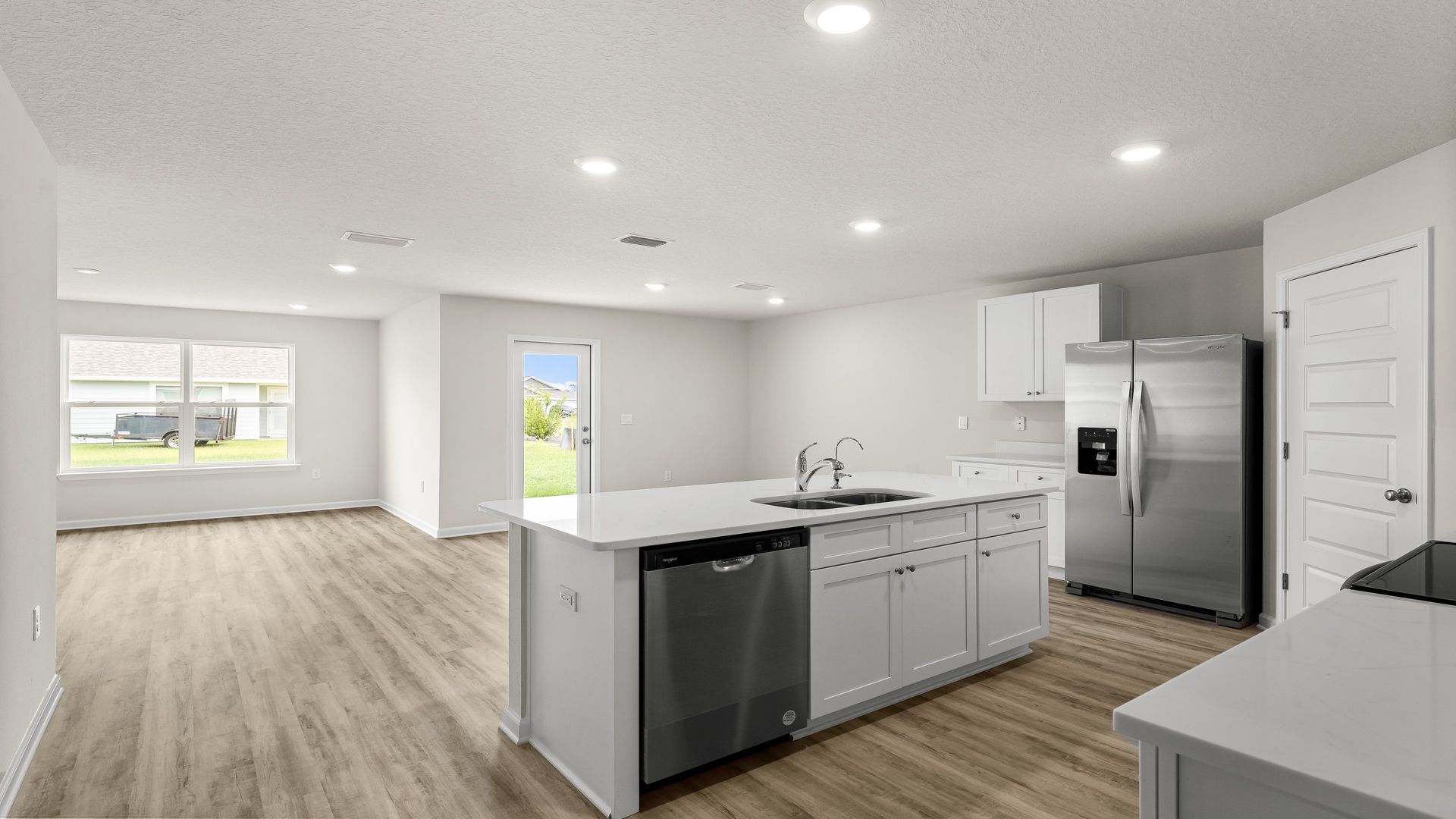 Kitchen island with white cabinets and stainless-steel appliances and quartz countertops.