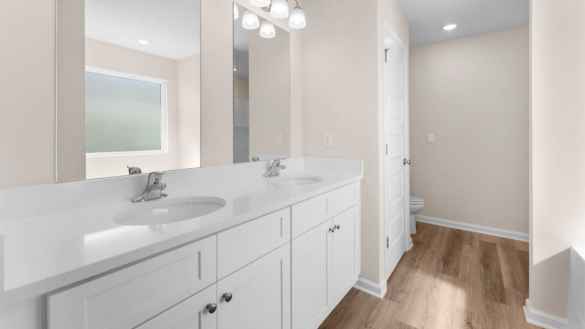 Primary bathroom with double vanity quartz countertops and tub and closet.