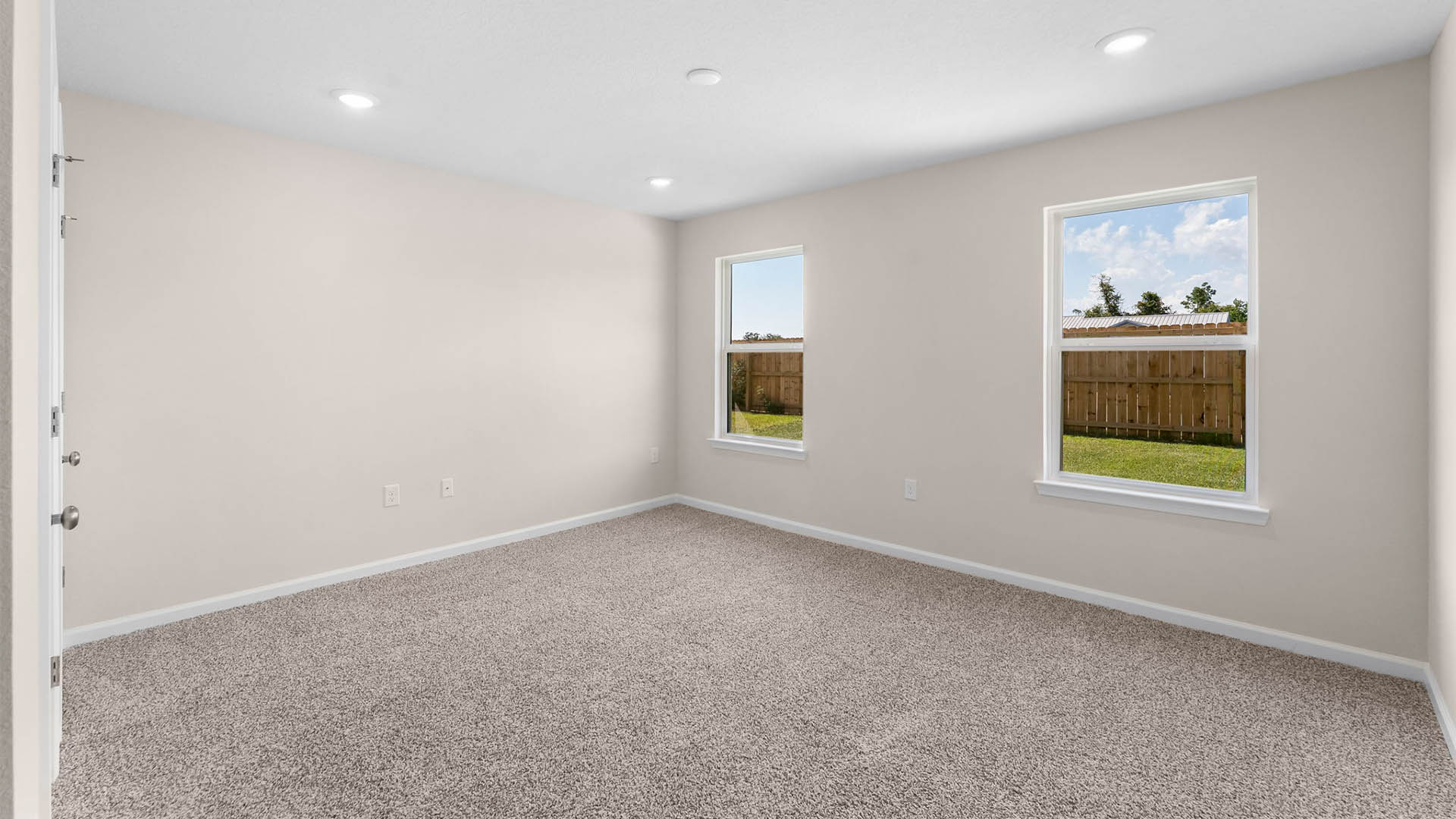 Primary bedroom with two windows and carpet floors.