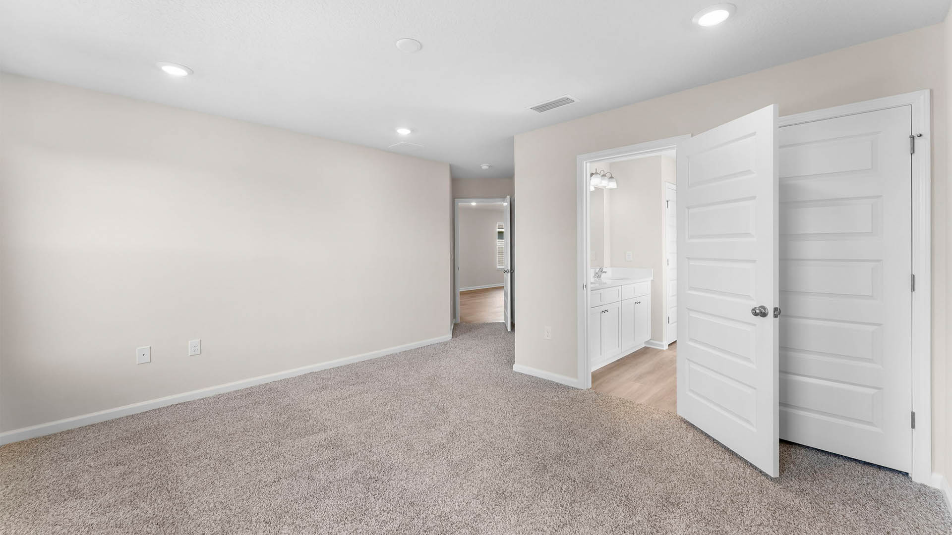 Primary bedroom with closet and bathroom entrance and carpet floors.