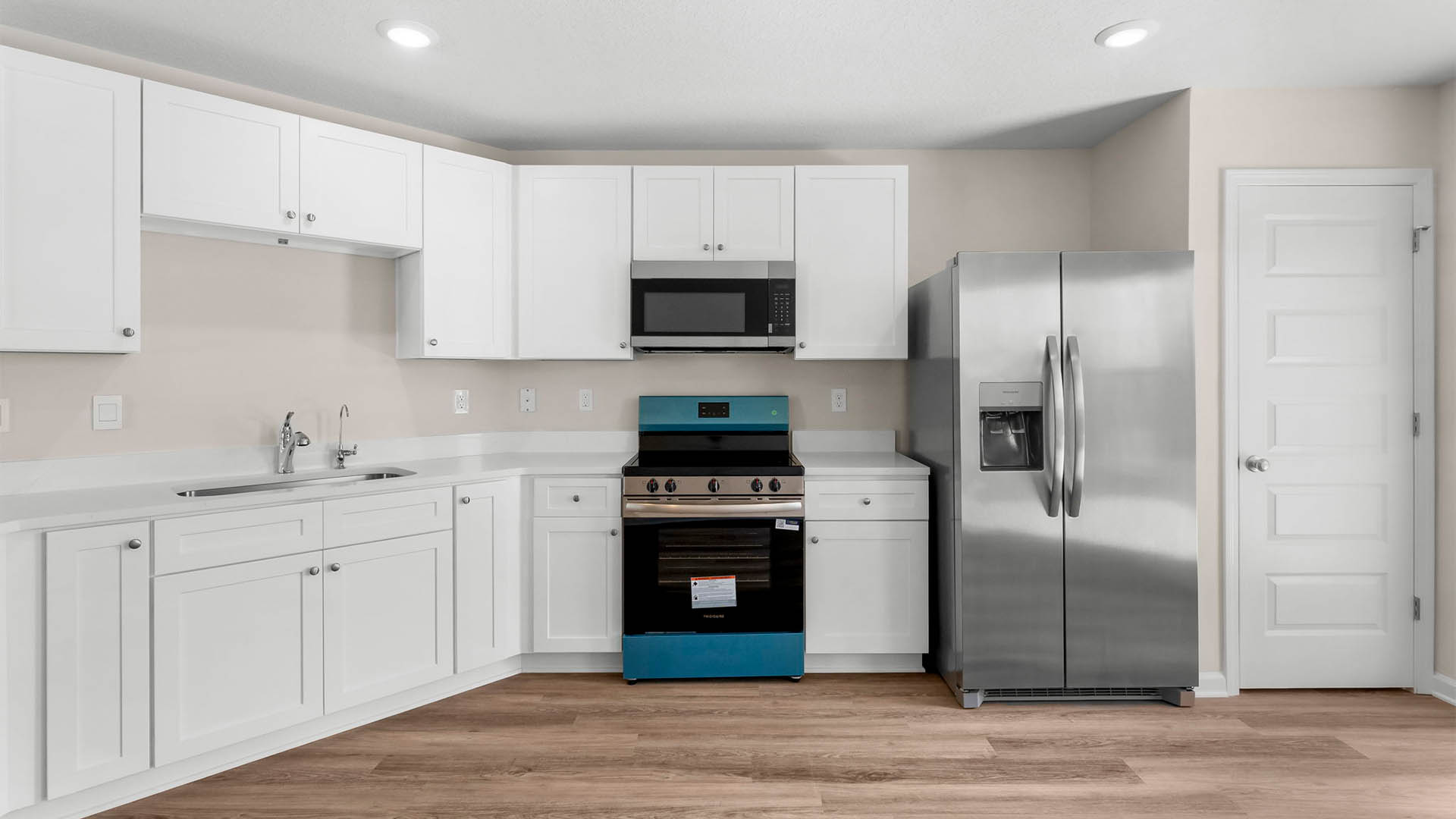Kitchen with quartz countertops and white cabinets with stainless steel appliances.