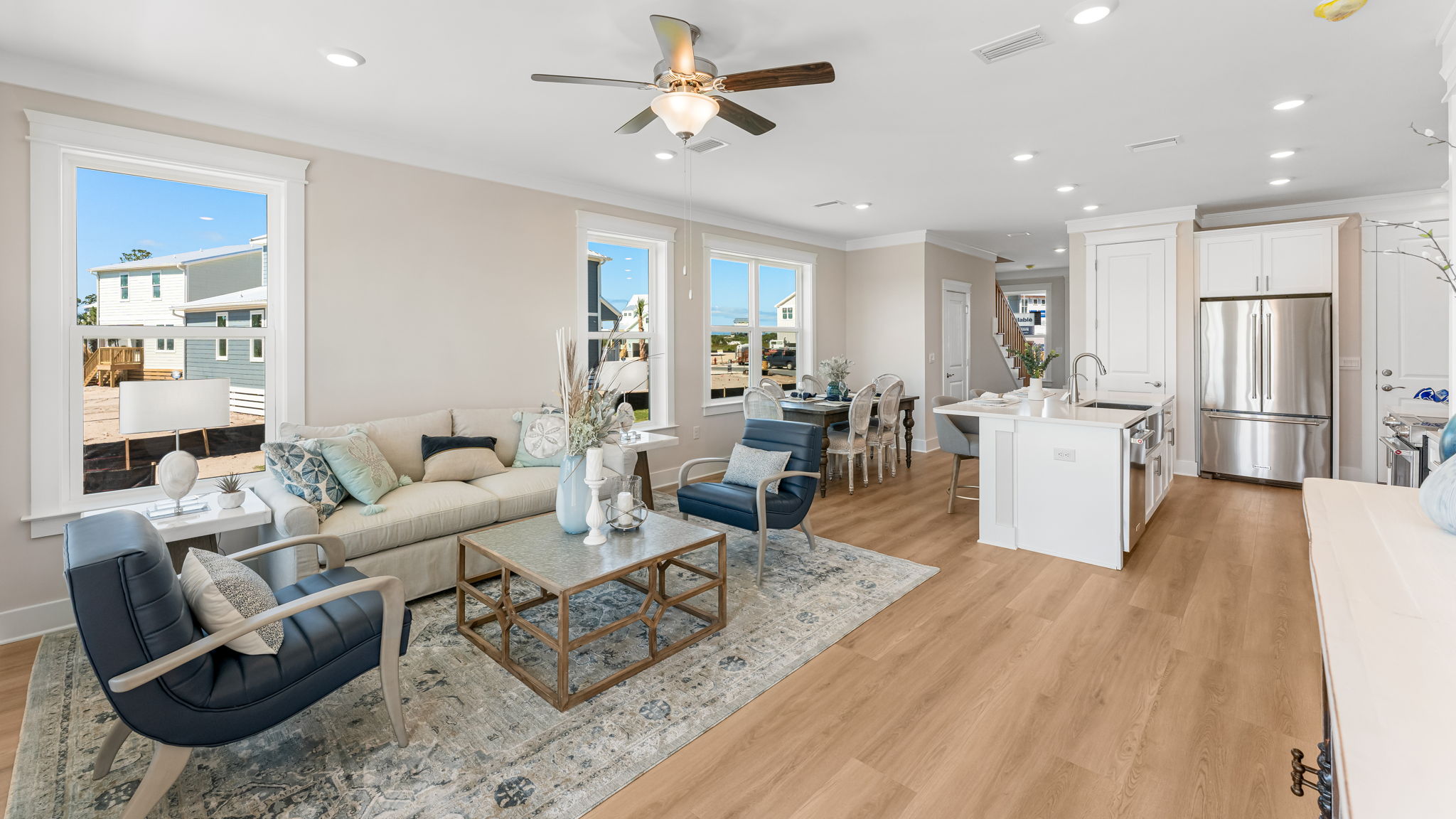 Open furnished living room with EVP flooring and ceiling fan and large windows.