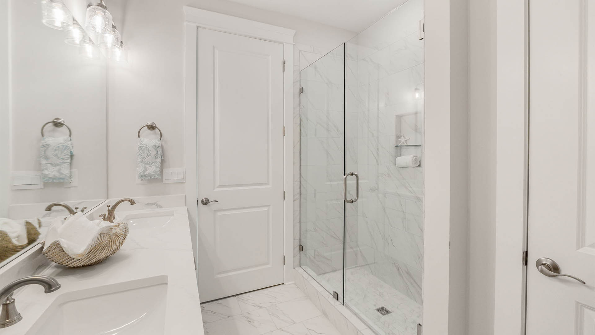 Bathroom with double-vanity and quartz countertops and walk-in shower.