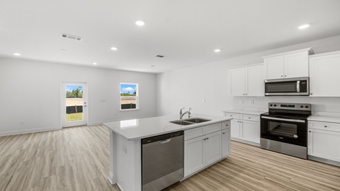 Kitchen with quartz countertops and stainless-steel appliances and island and white cabinets.