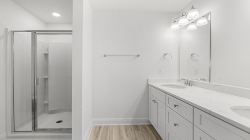 Bathroom with double vanity quartz counter tops and shower with glass door.