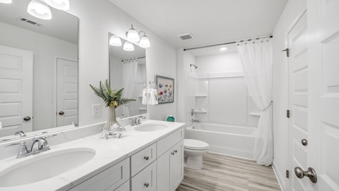 Bathroom with white quartz countertops and double vanity and shower and toilet.