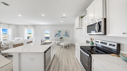 Furnished kitchen and dining room with white cabinets and quartz countertops and island.