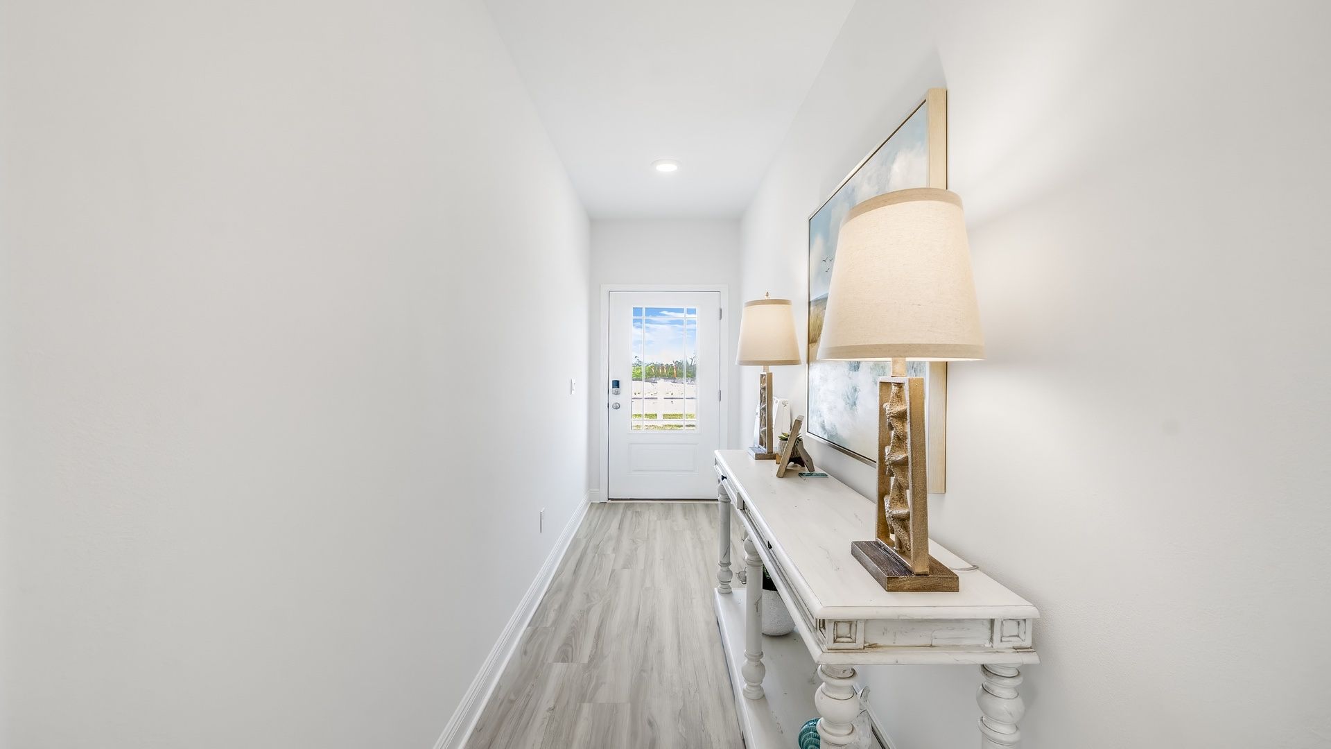 Front hallway with white furniture and picture in model home.