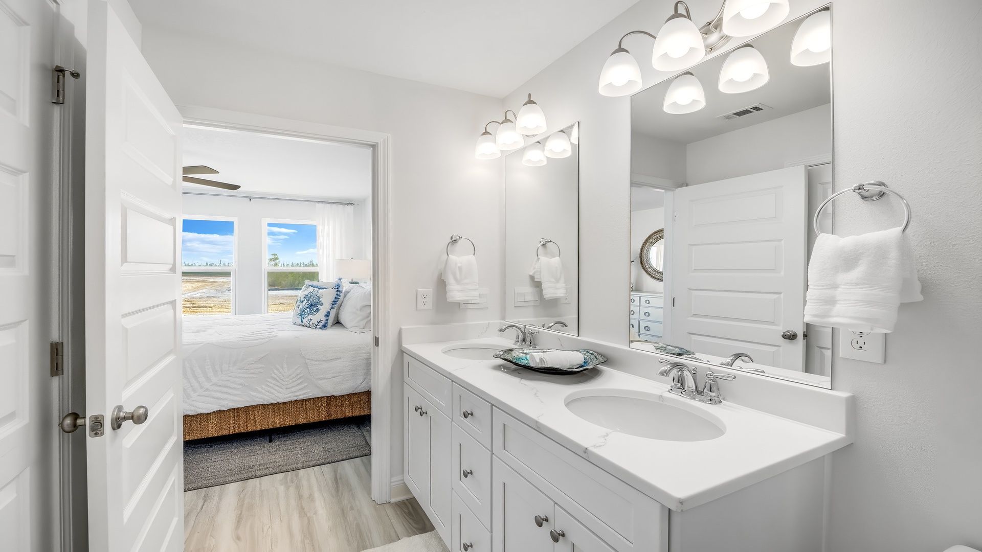 Primary bathroom with white quartz countertops and double vanity and bedroom doorway.