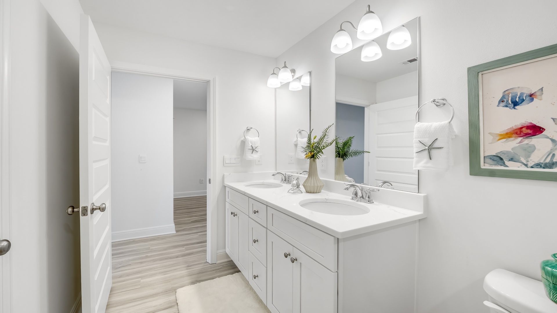 Bathroom with white quartz countertops and double vanity and white cabinets.