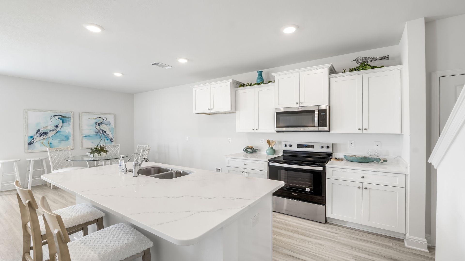 Furnished kitchen and dining room with white cabinets and quartz countertops and island.