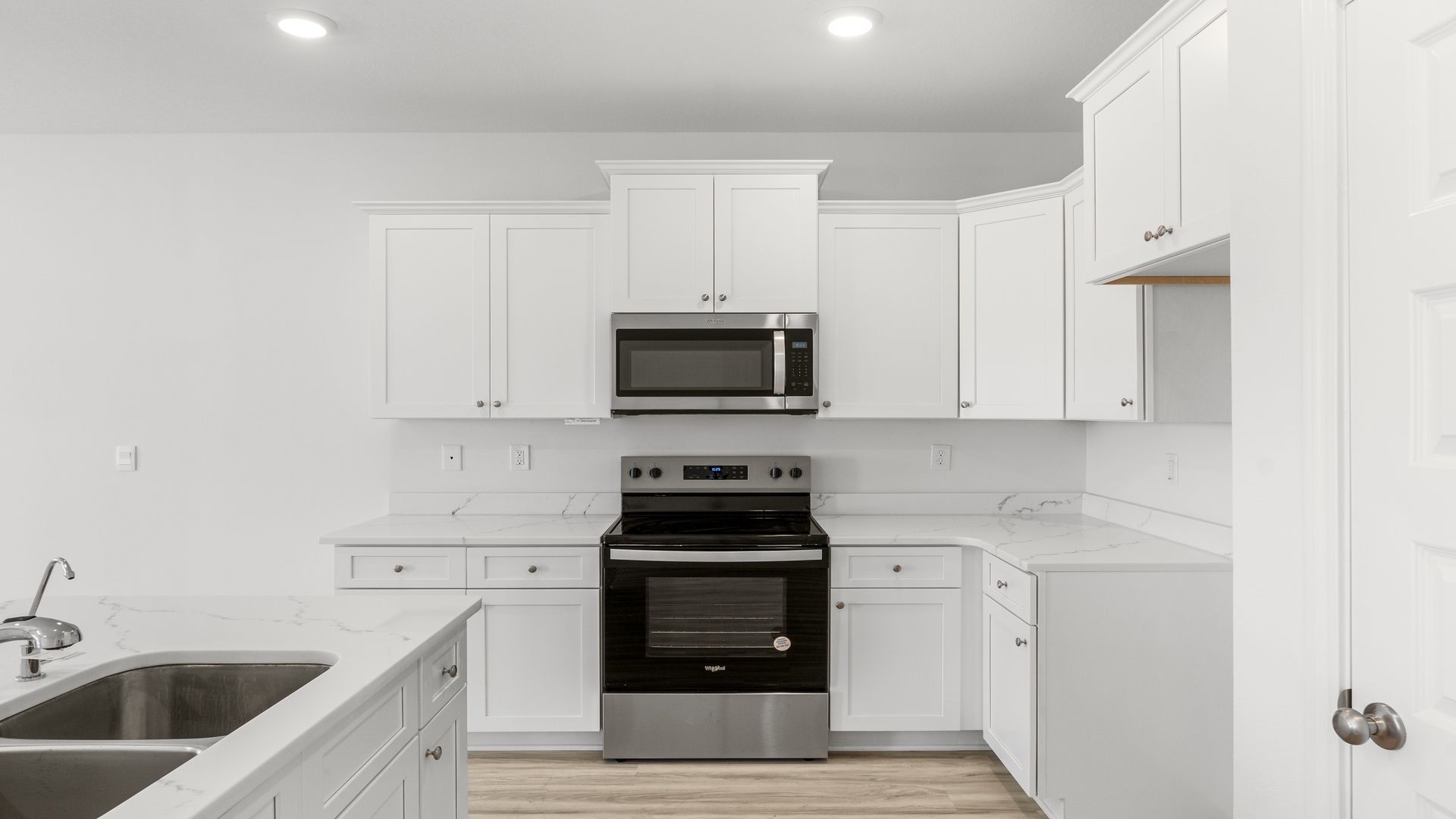Kitchen with quartz countertops and stainless-steel appliances and island and white cabinets.