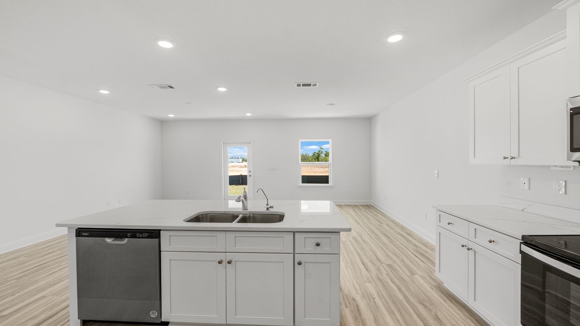 Kitchen with quartz countertops and stainless-steel appliances and island and white cabinets.