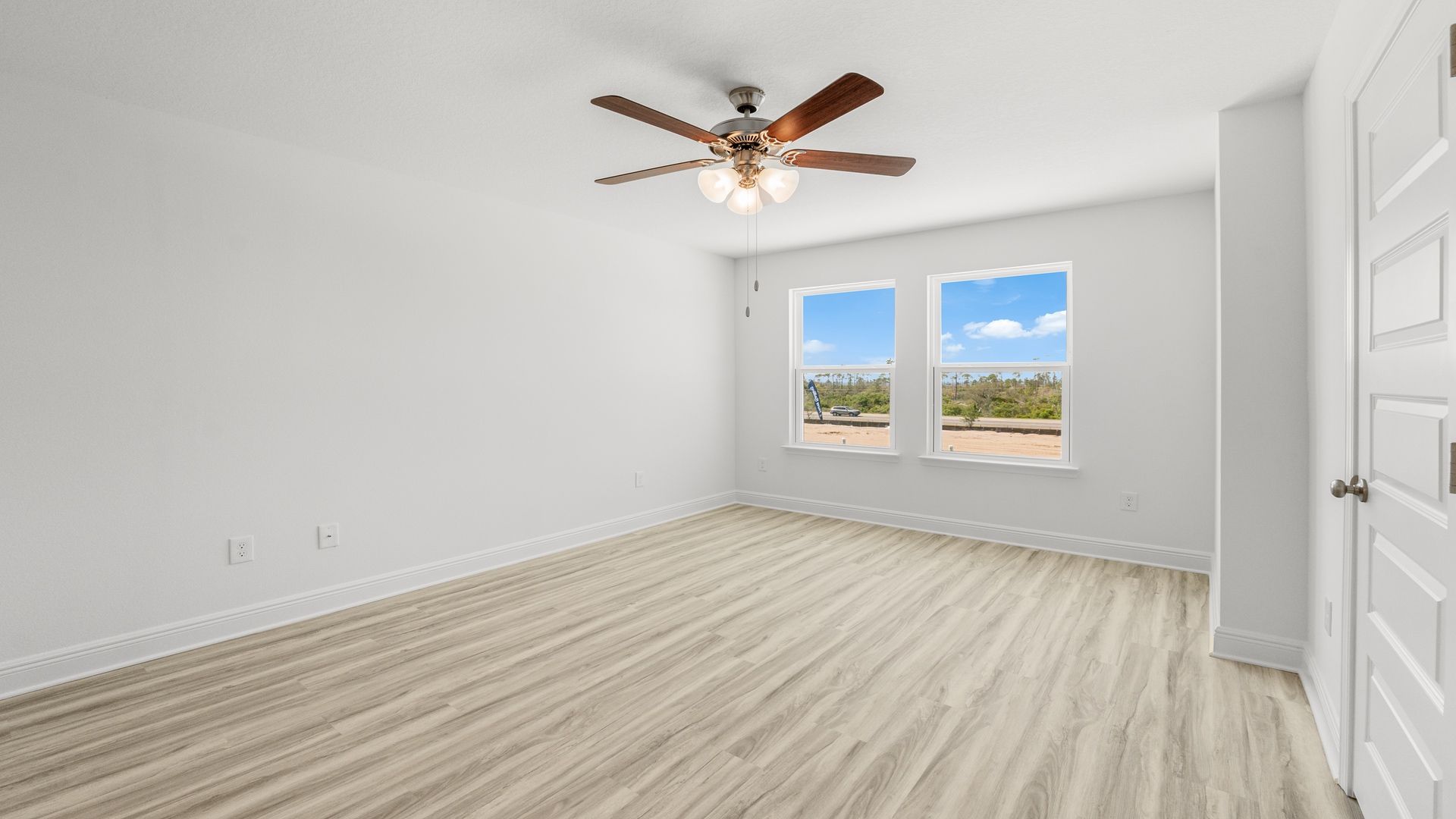 Bedroom with EVP flooring and ceiling fan and two windows.