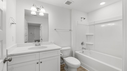 Bathroom with single vanity and quartz countertop and white cabinets and shower and toilet.
