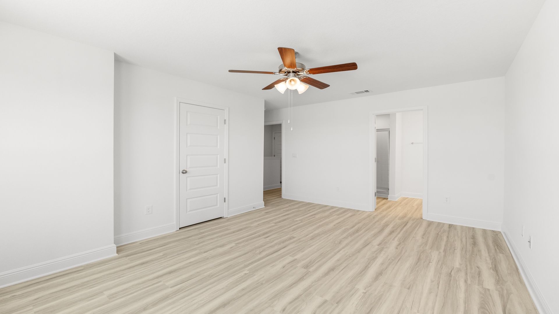 Bedroom with EVP flooring and ceiling fan and bathroom entrance.