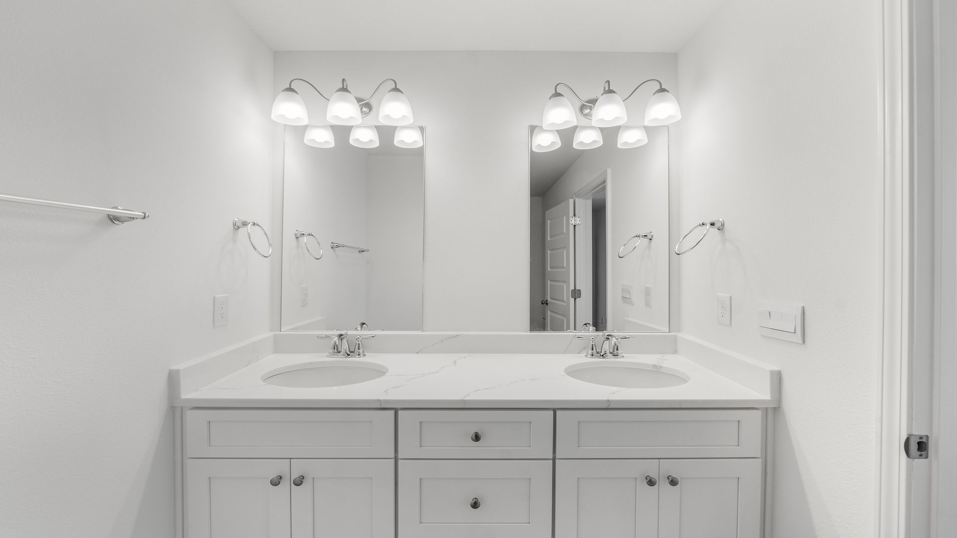 Bathroom with double vanity and quartz countertops and white cabinets.