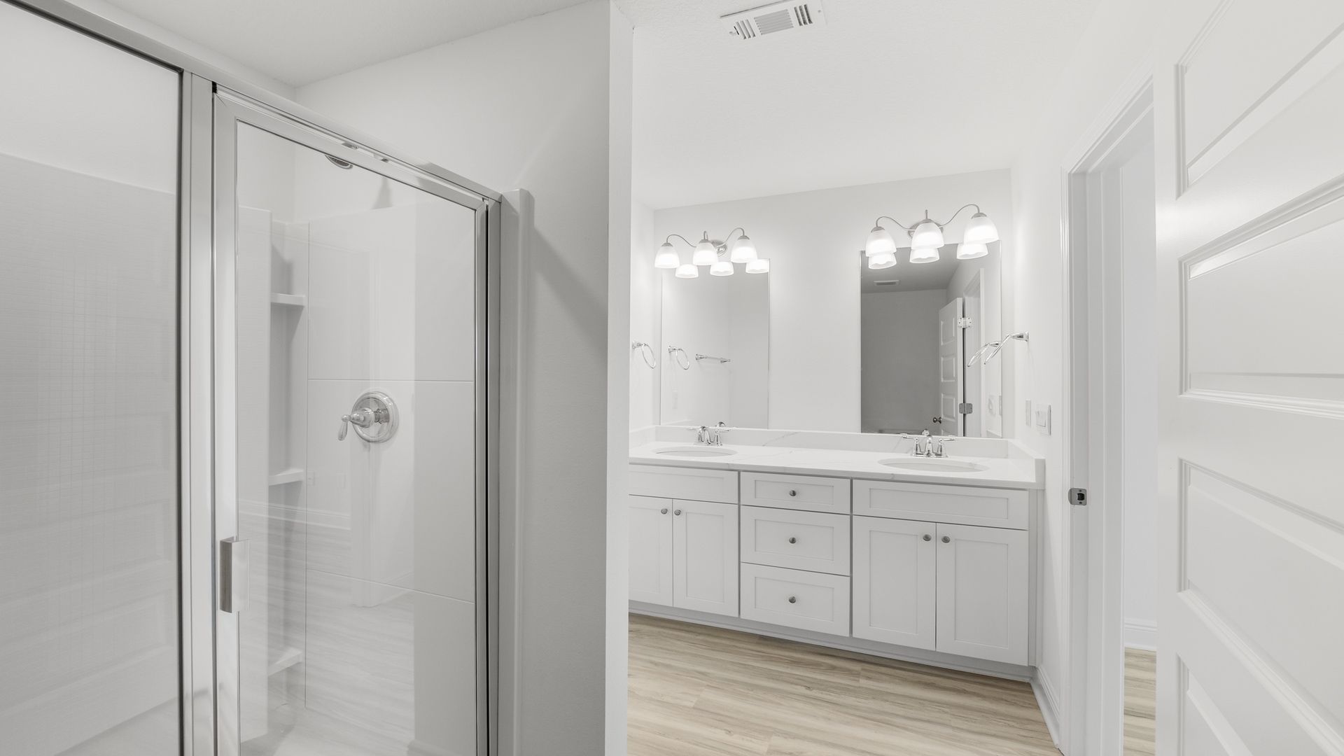 Bathroom with double vanity quartz counter tops and shower with glass door.