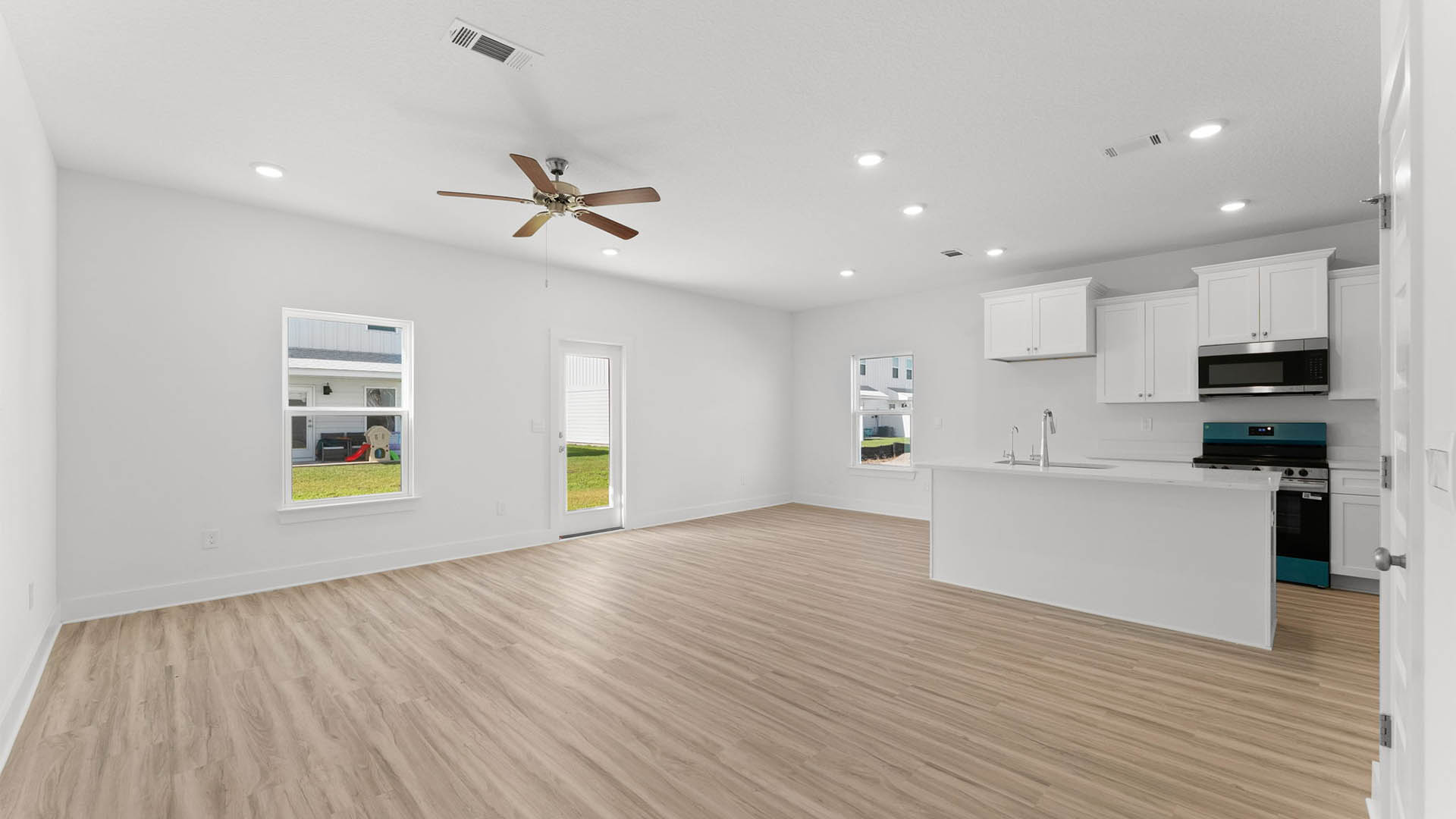 Open kitchen and living room with ceiling fan and EVP flooring.