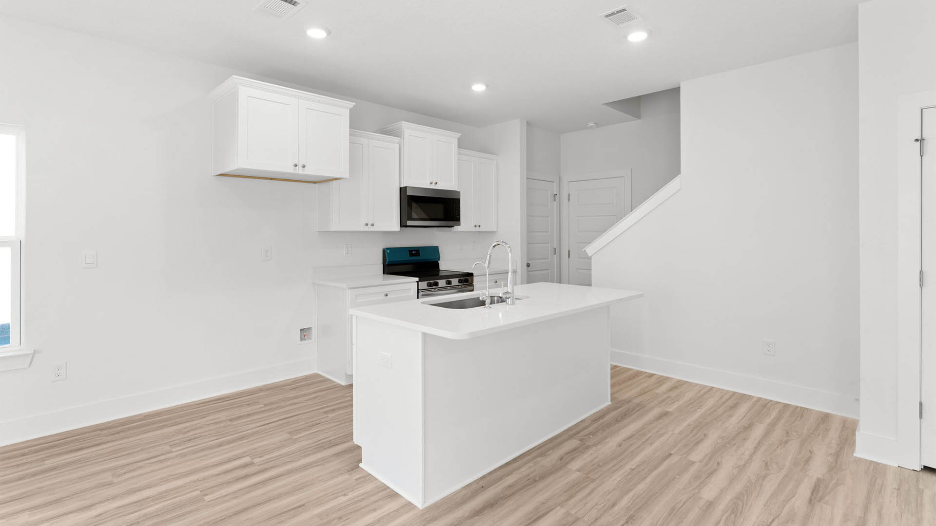 Kitchen with stainless-steel appliances and white cabinets and quartz countertops and island.
