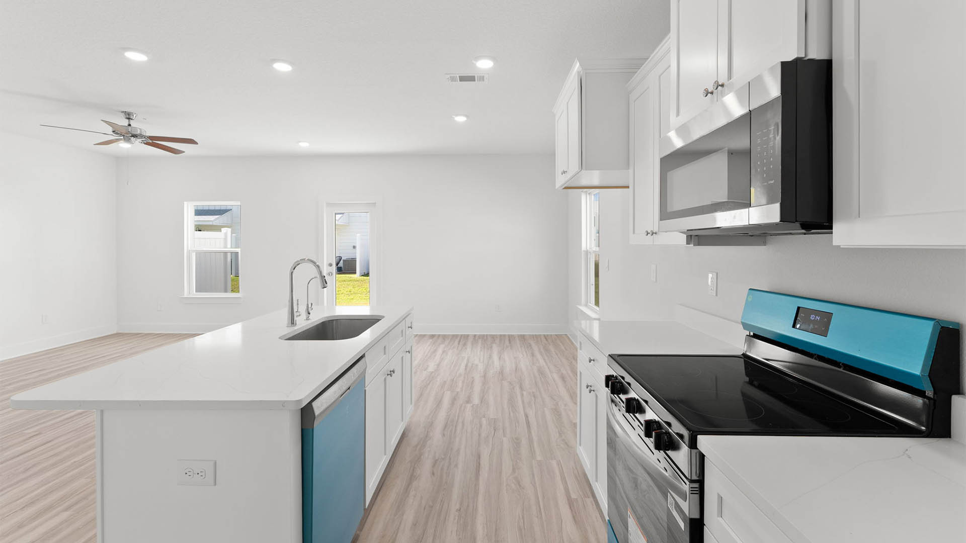 Kitchen with stainless-steel appliances and white cabinets and quartz countertops and island.