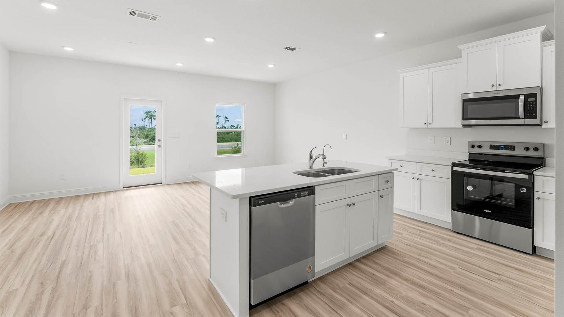 Kitchen with quartz countertops and stainless-steel appliances and island and white cabinets.