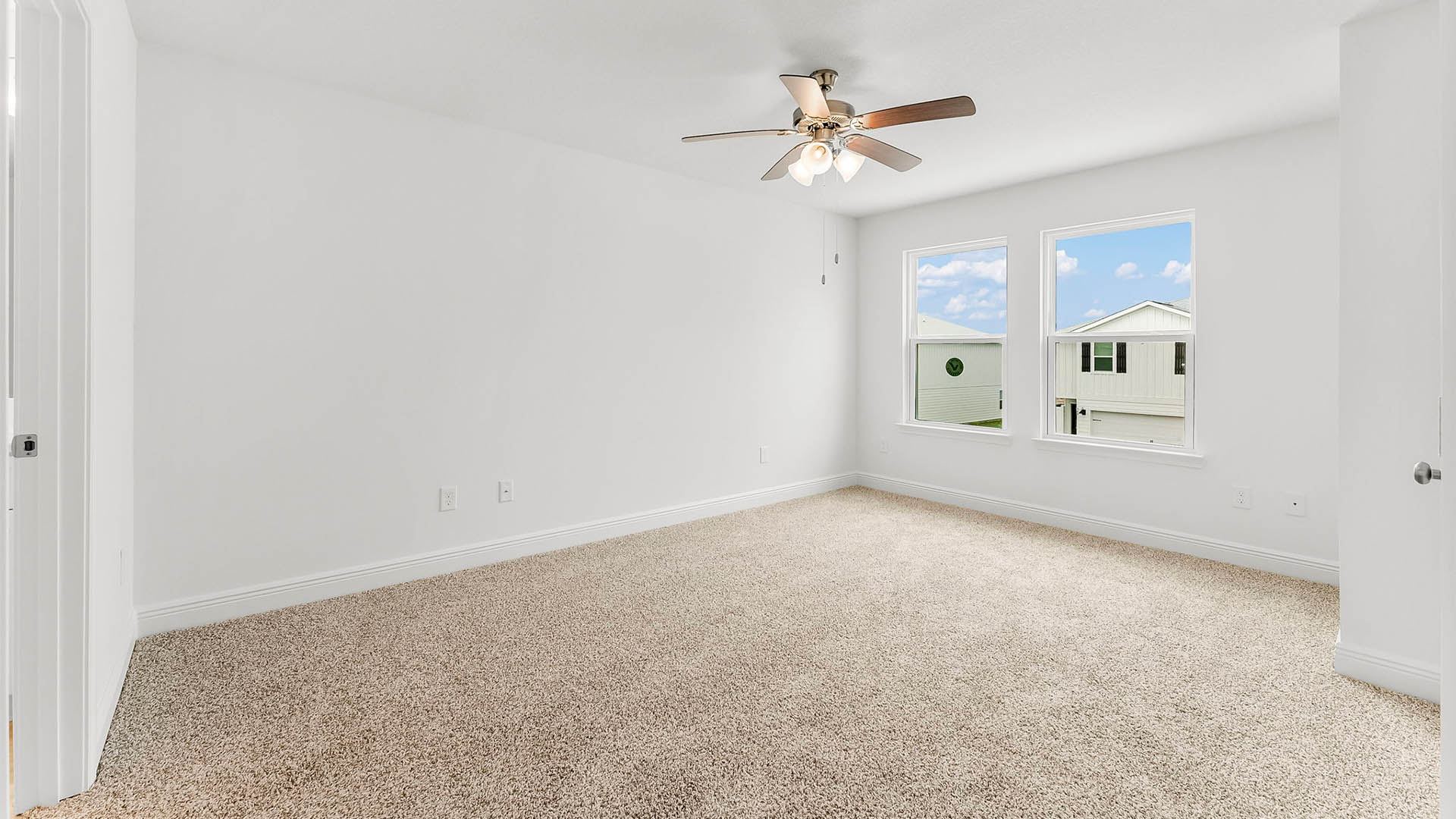 Primary bedroom with carpet floors and ceiling fan and two windows.