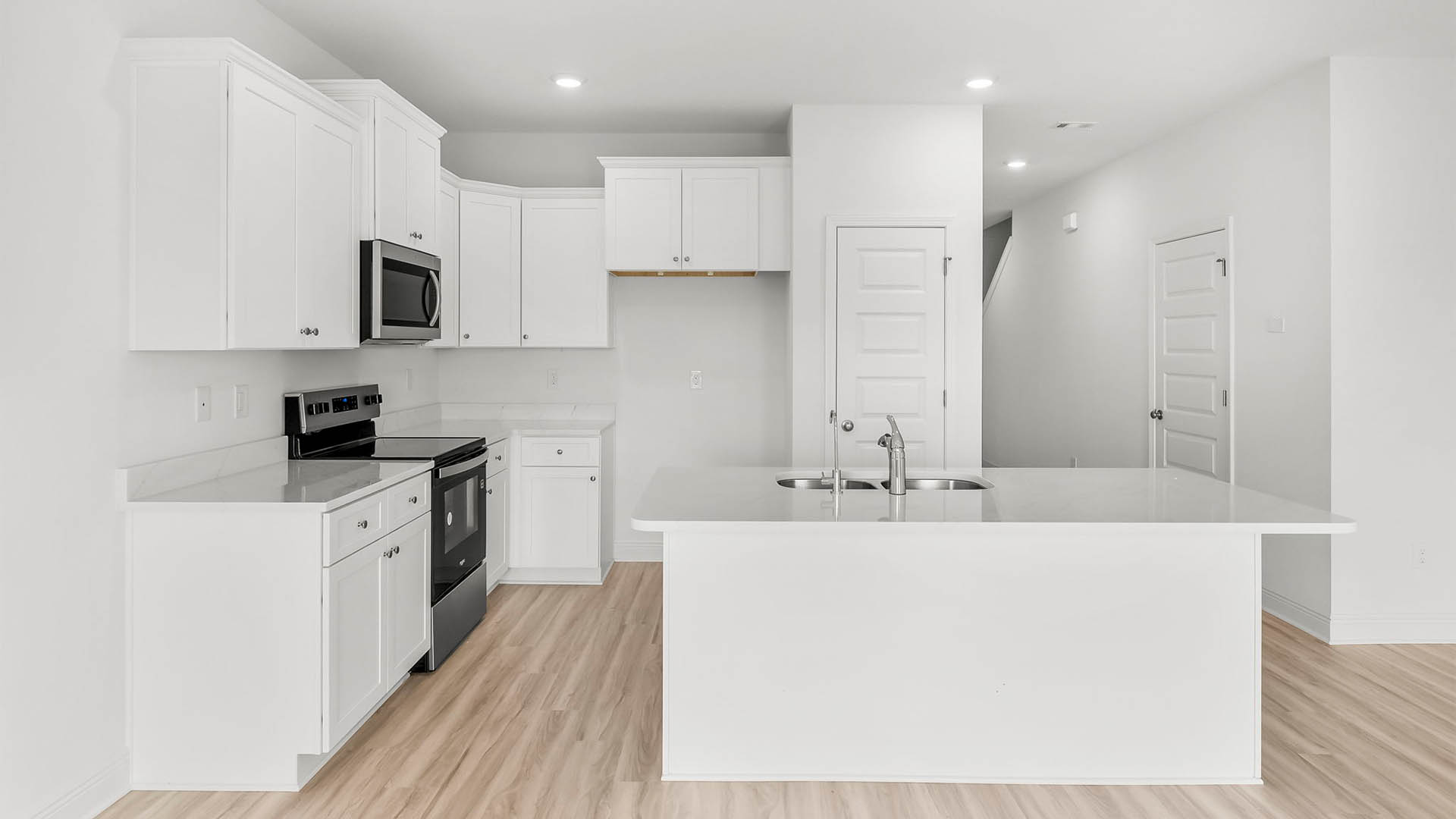 Kitchen with quartz countertops and stainless-steel appliances and island and white cabinets.