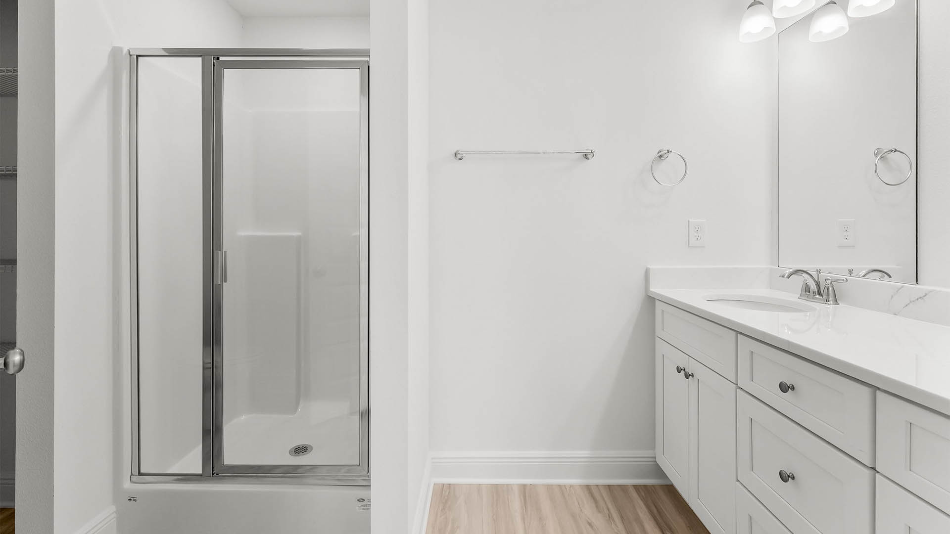 Primary bathroom with double vanity quartz counter tops and shower with glass door.