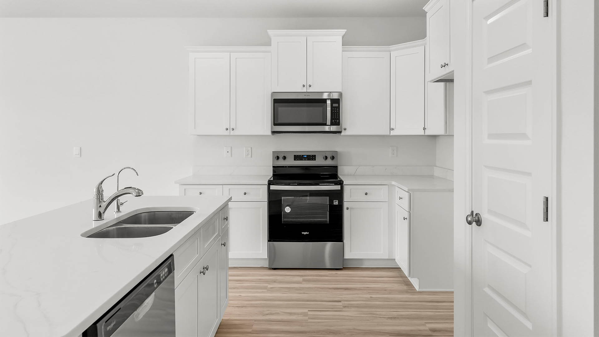 Kitchen with quartz countertops and stainless-steel appliances and island and white cabinets.