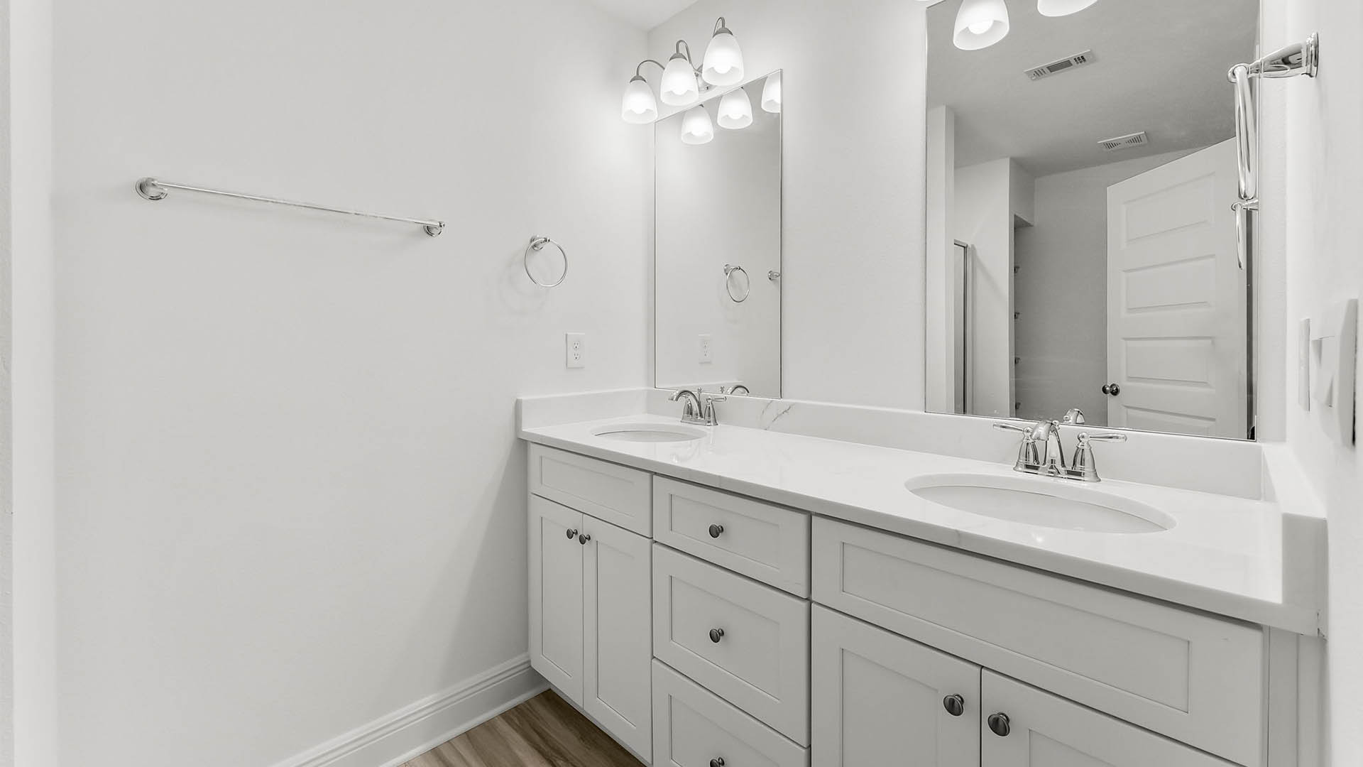 Primary bathroom with double vanity and quartz countertops and white cabinets.