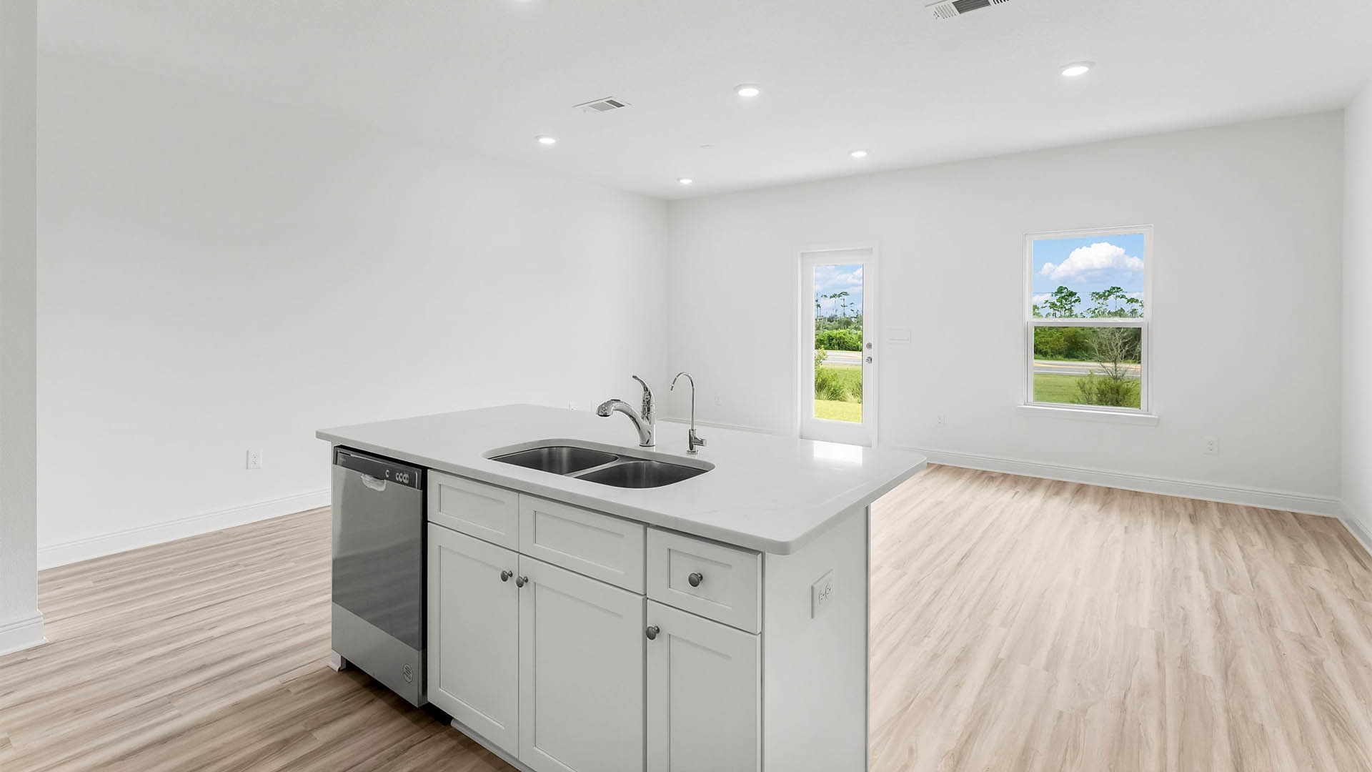 Kitchen with quartz countertops and stainless-steel appliances and island and white cabinets.