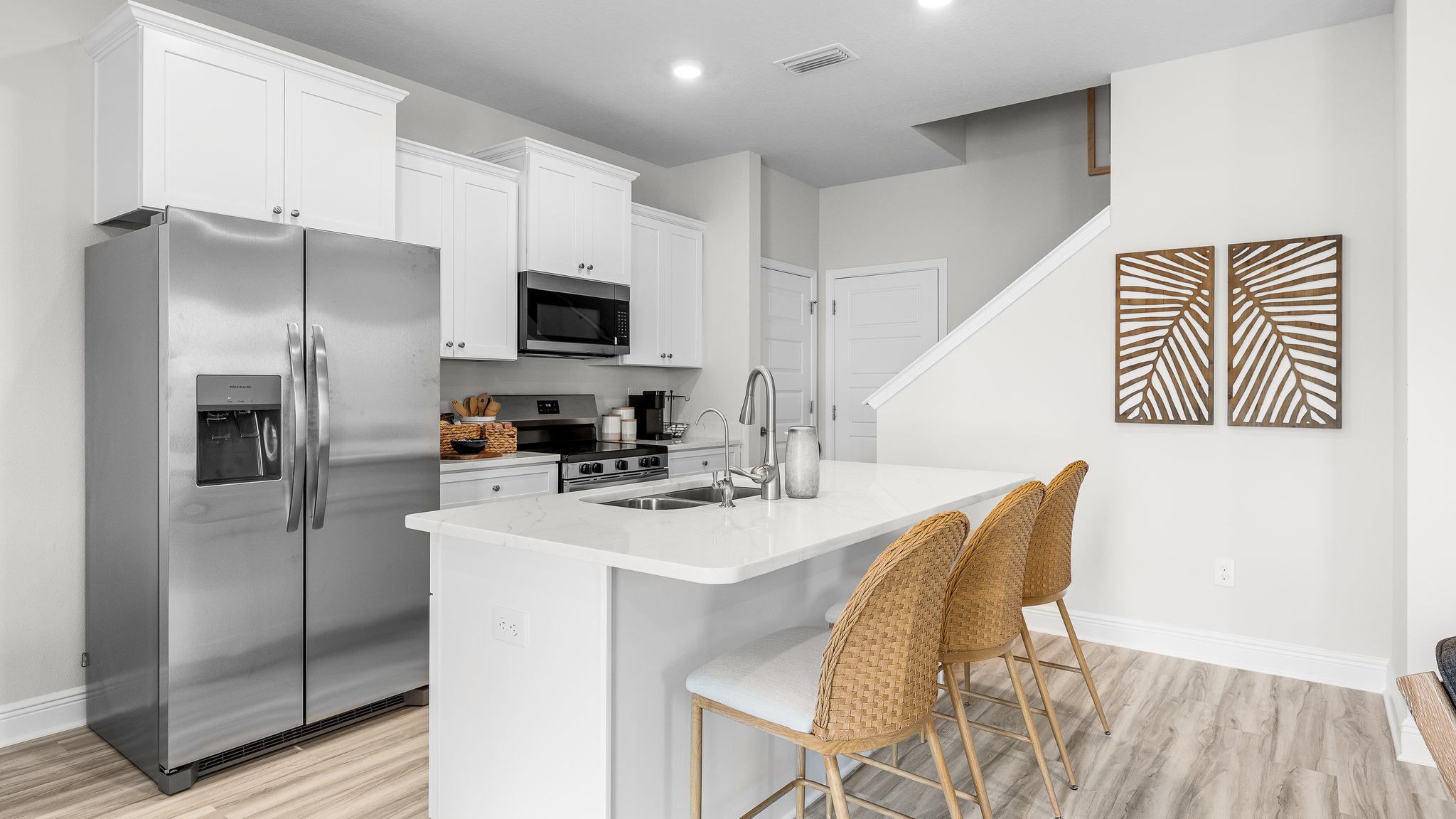Kitchen with island and quartz countertops and stainless steel appliances and white cabinets.