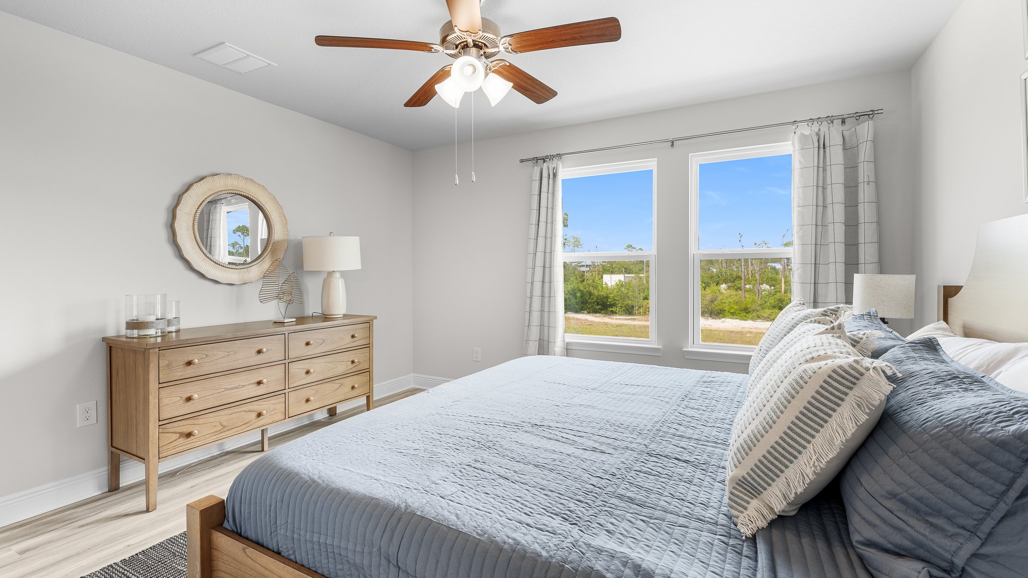 Primary bedroom with ceiling fan and EVP flooring and windows.