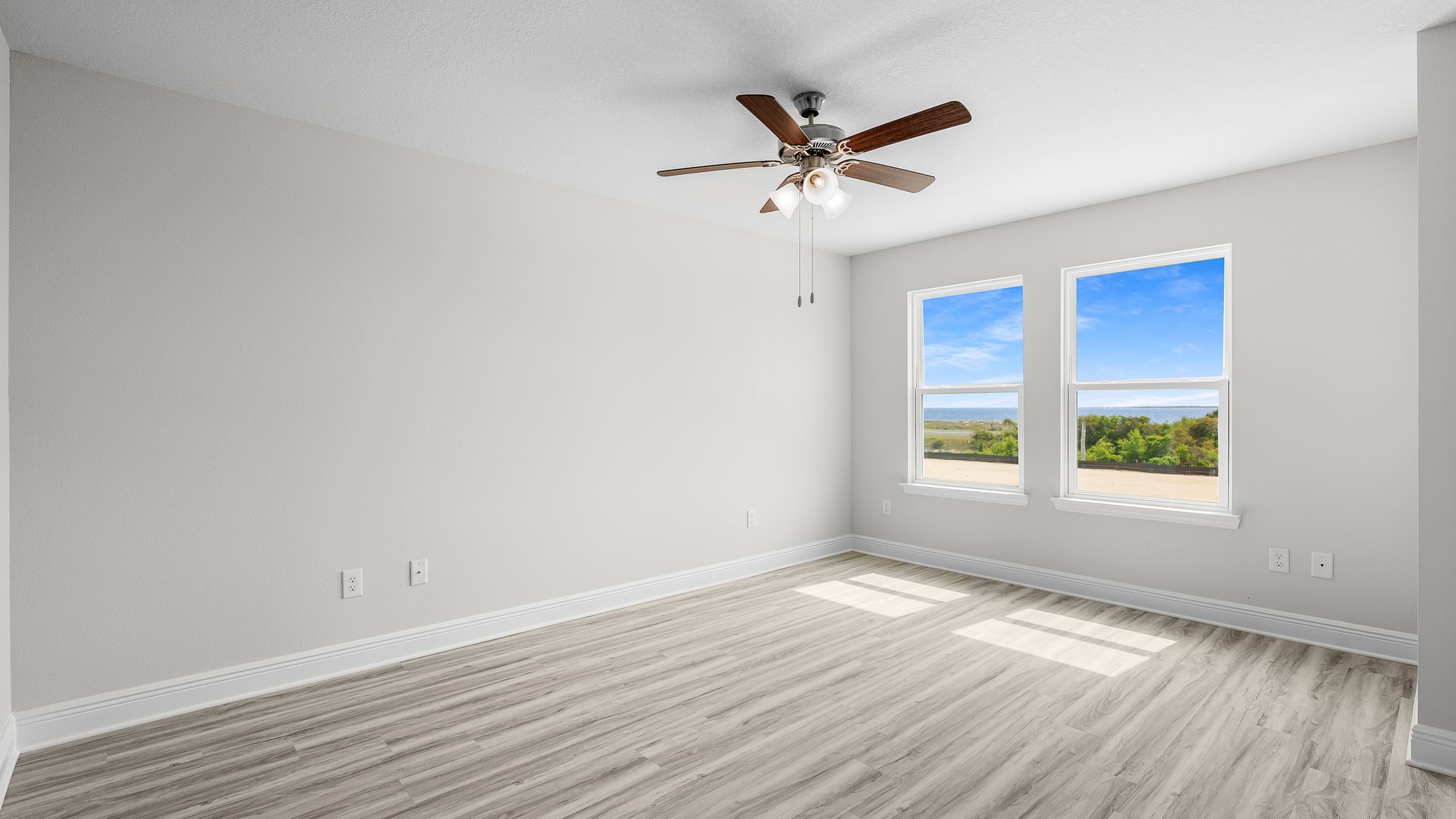 Primary Bedroom with EVP flooring and ceiling fan and two windows.