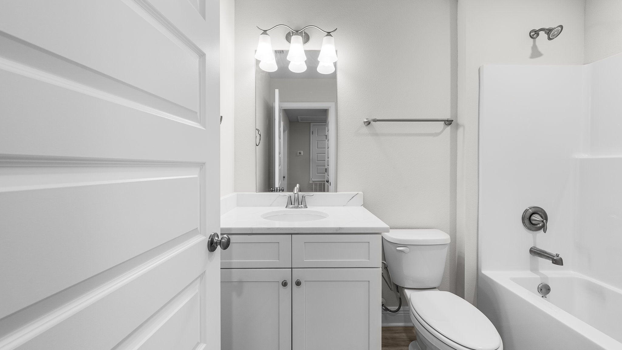 Bathroom with single vanity and quartz countertop and white cabinets and shower and toilet.