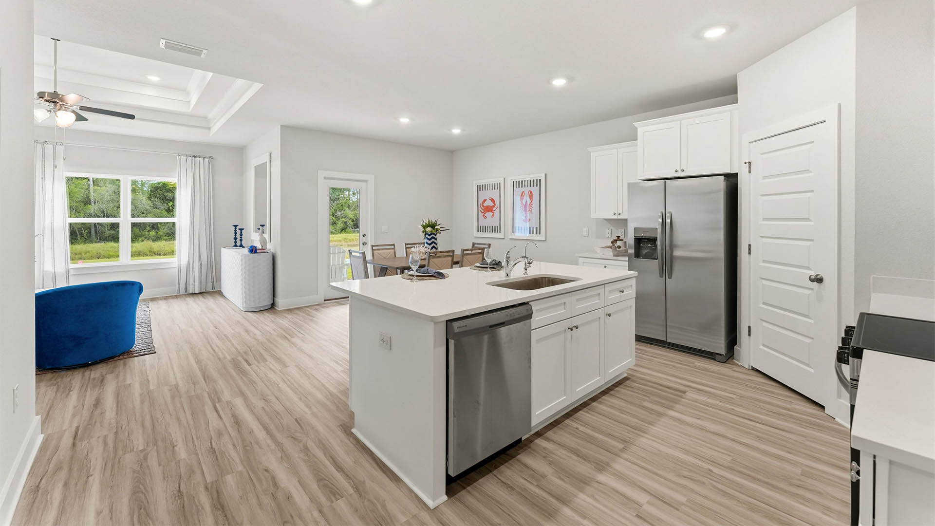 Kitchen with quartz countertops and white cabinetry and island and stainless-steel appliances and pantry.