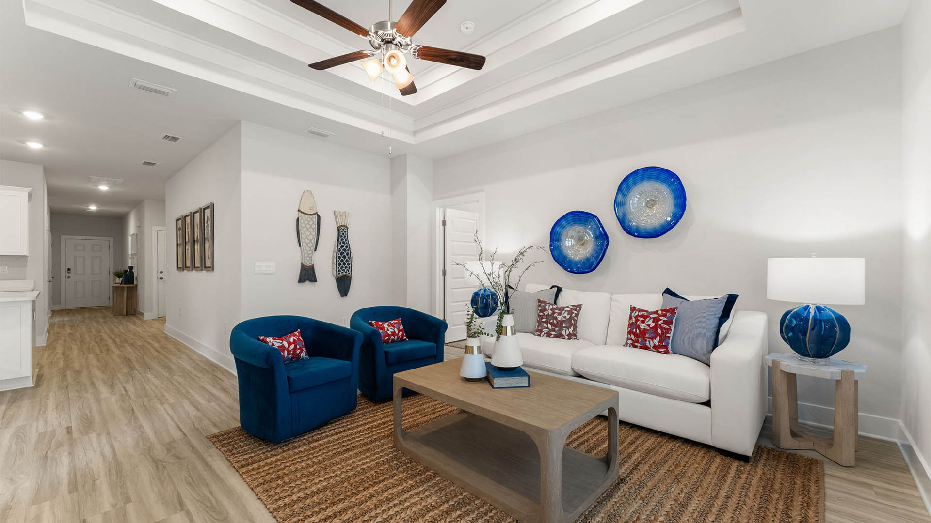Living room with EVP flooring and tray ceilings and ceiling fan and kitchen.