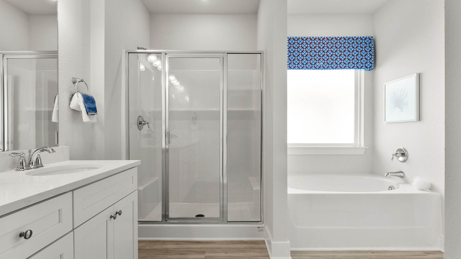 Primary bathroom with glass shower doors and tub with window.