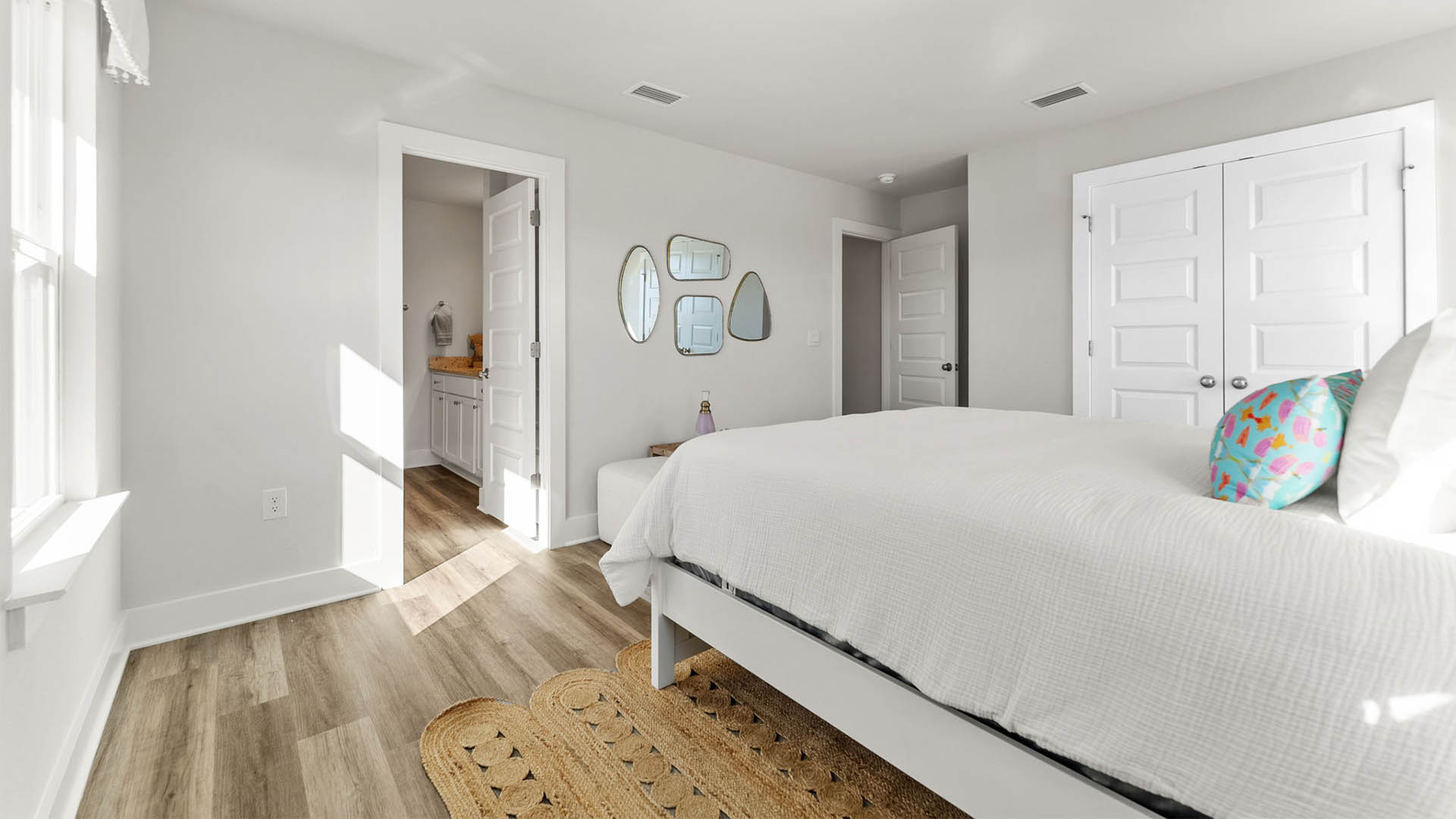 Primary bedroom with EVP flooring with ceiling fan and window and bathroom entrance.