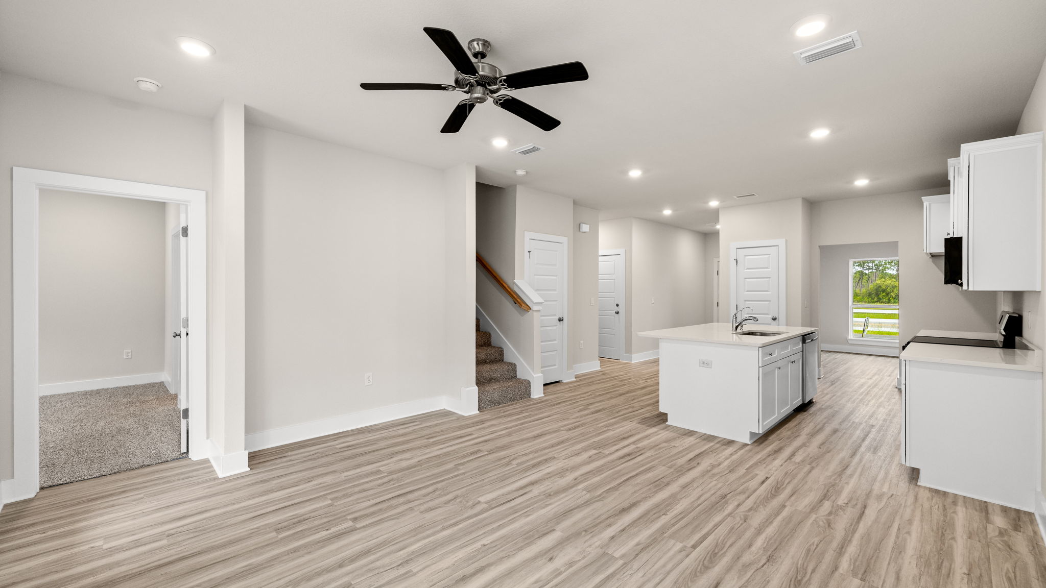 Living room with ceiling fan and EVP flooring and kitchen.