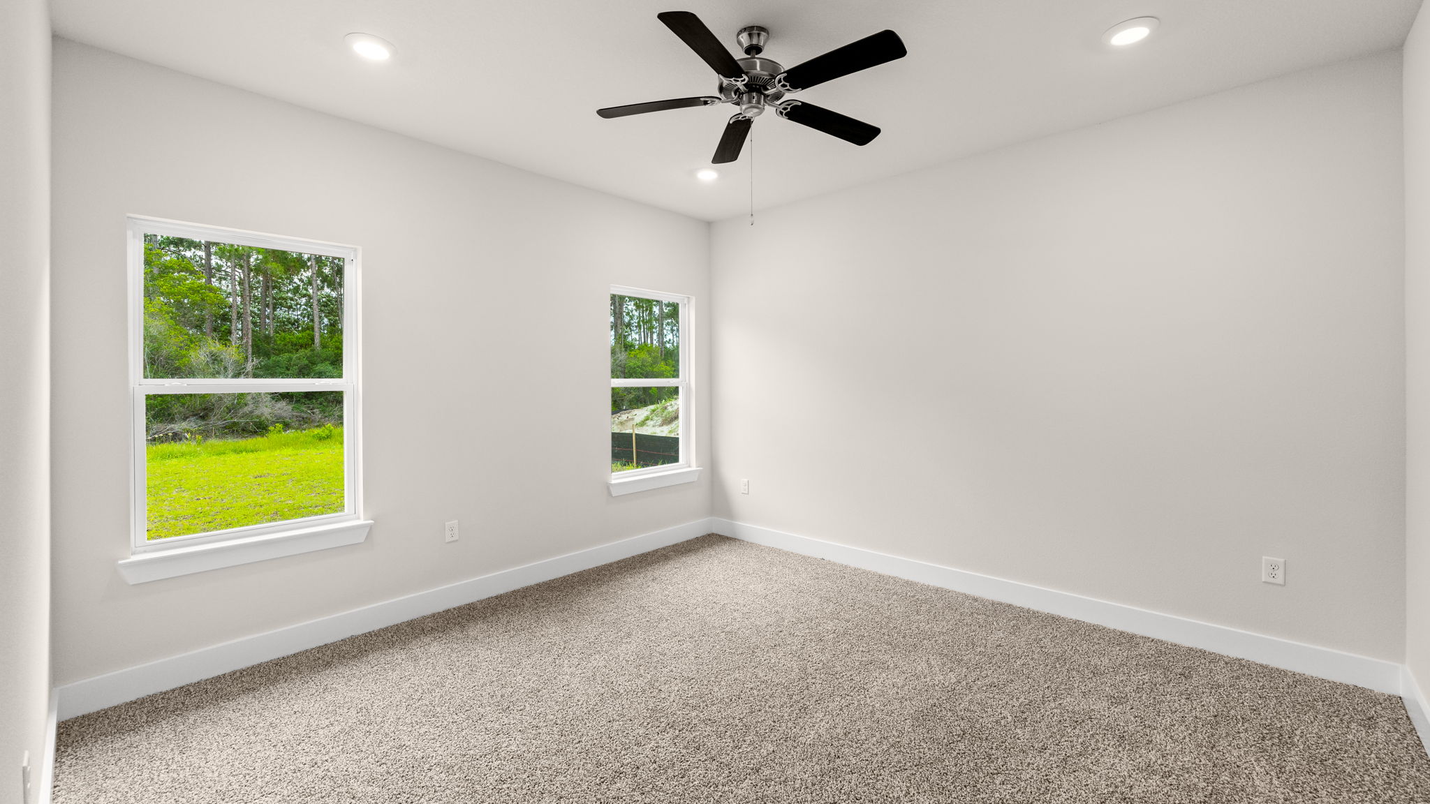 Primary bedroom with carpet flooring with ceiling fan and window and bathroom entrance.