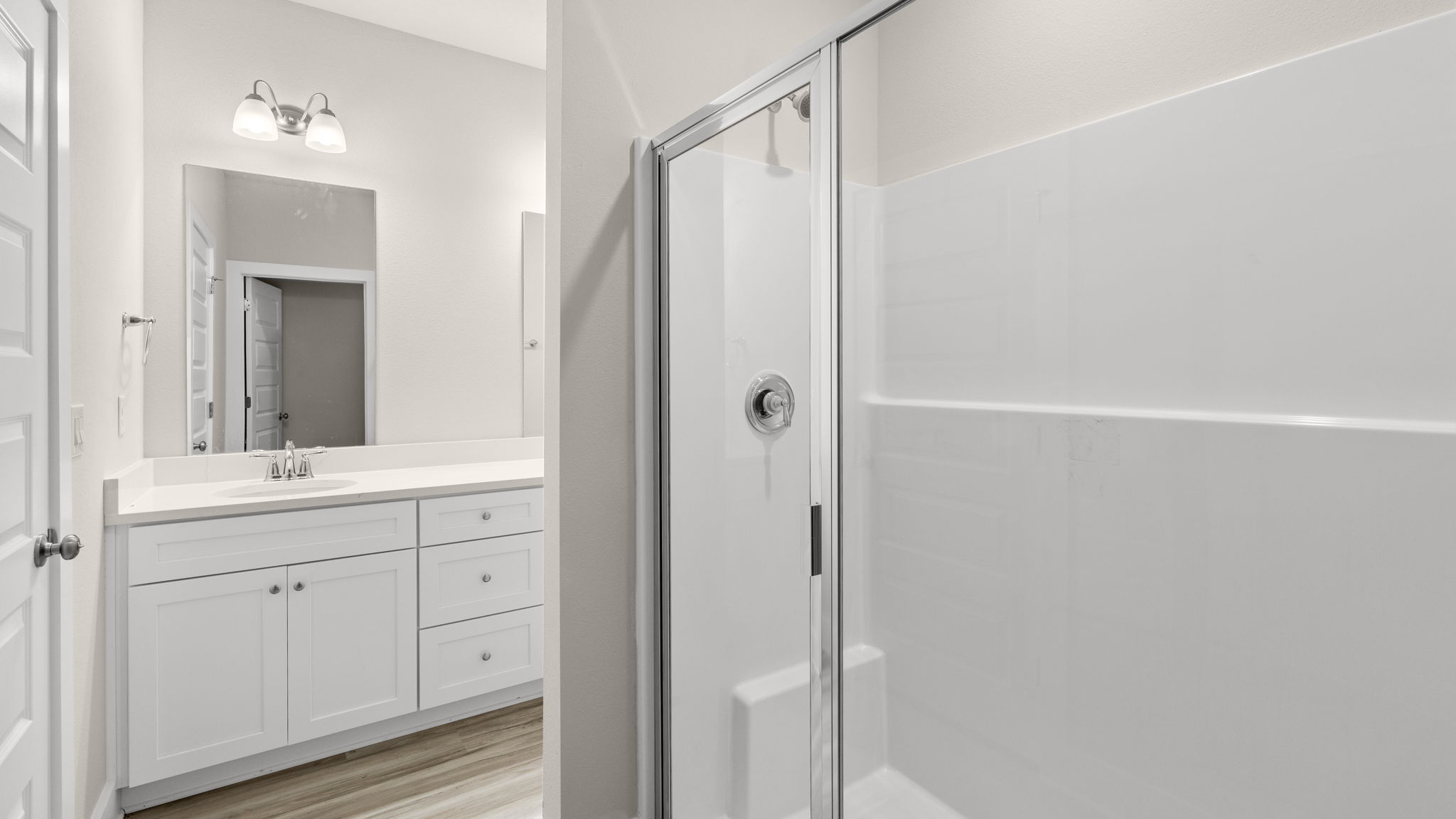 Primary bathroom with double vanity quartz countertops and white cabinets and shower and closet with EVP flooring.